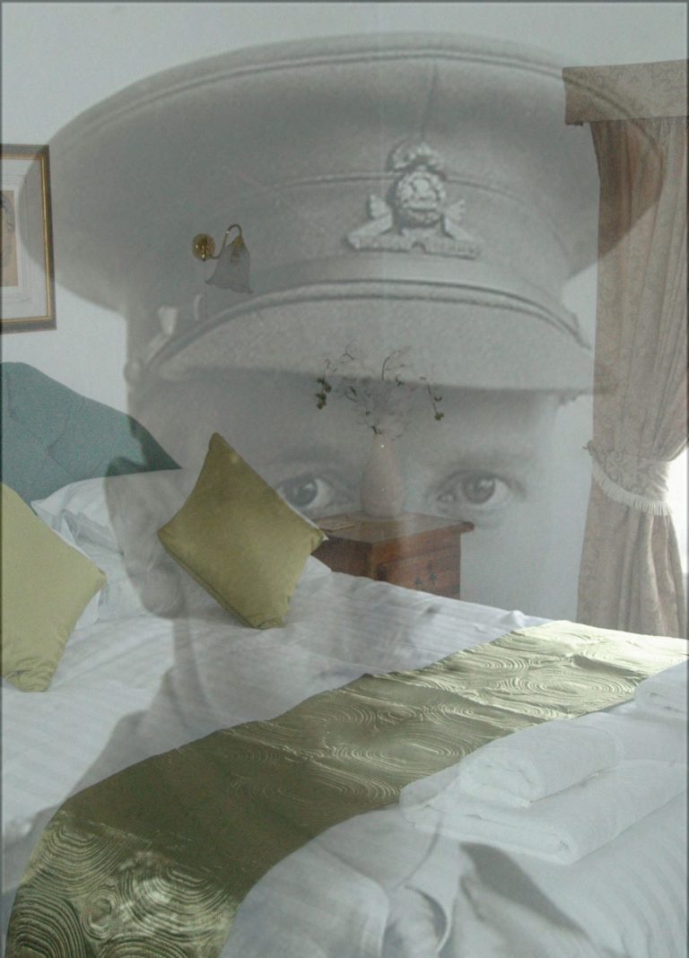 A soldier's portrait overlays a neatly made bed with decorative cushions.