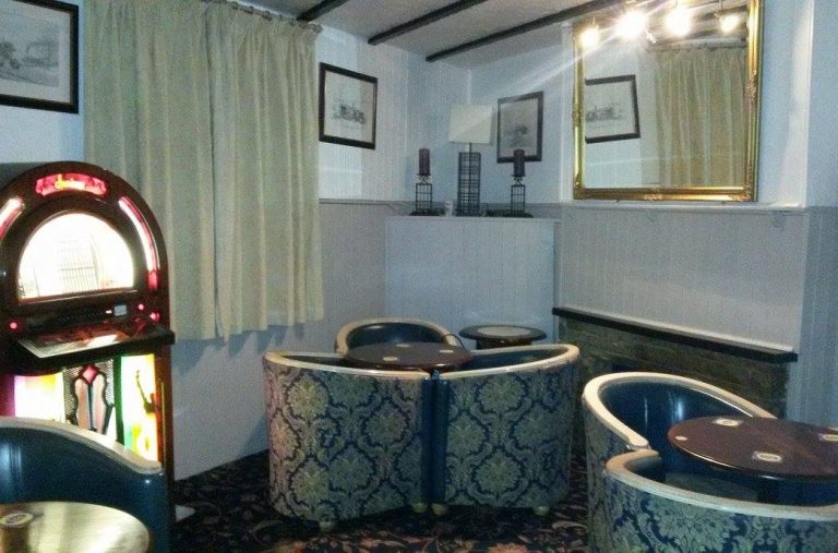 Cozy pub interior featuring a jukebox, round tables, and traditional decor.